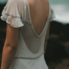 The Iona gown by Amanda Garrett is truly stunning. Silk chiffon gown with hand applied crystal draped beading detail on neckline sleeves and drop front waistline, utterly unique, worn here with silk low back slip, may be ordered with a higher back. This designer wedding dress is available to try on at The Barefaced Bride studio.