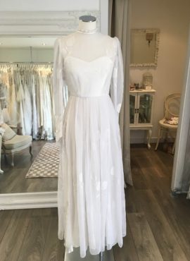 This beautiful vintage gown is from the 1970s. Featuring white chiffon, long sleeves with rose flower embroidery. This vintage dress is available to try on at The Barefaced Bride studio.
