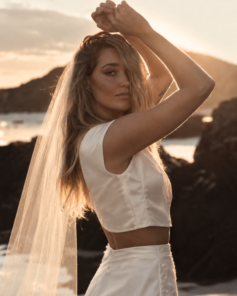 Bride wearing a white satin two-piece wedding outfit with a veil.